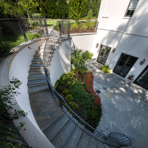 View of small garden that is part of enclosed patio/courtyard with curved staircase
